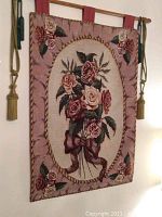 Full view of the floral rose wall hanging tapestry hanging on a rod with tassel decorations visible on sides.