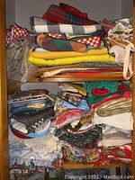 Folded assorted linens stacked on shelves in various colors, patterns including plaids, checks, and solids.