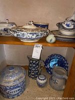 Overall view showing multiple blue and white ceramic dishes, creamers, casserole dish with lid, and a butter crock with lid labeled 'BUTTER.'