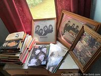 Photo showing stack of Beatles books including LIFE Beatles magazine, framed Beatles-themed mirror with band silhouette, and other framed wall art