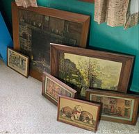 Grouping of six vintage framed wall art prints on carpet against a wall near window with curtains