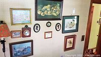 Full wall display of various framed art pieces and thermometer showing the lot contents and arrangement.