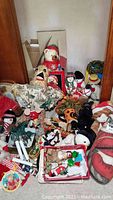 Photo showing a collection of plush holiday-themed items including Santa Claus, pumpkin figures, and snowmen, as well as hanging ornaments and decorations.