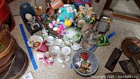 Overview photo showing multiple toys, Easter-themed items, ceramic and glass pieces, mid-century tea set, and plush figures arranged on floor.