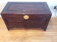 Top view of the rectangular carved wooden trunk showing intricate Chinese designs and central brass clasp.
