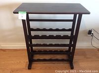 Front view of wood wine rack showing dark finish, four rows of curved holders, and solid top surface.