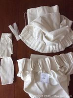 Top view of white fabric drape panels along with fabric ties and an iron-on hem piece, highlighting the pleated and flat panel styles.