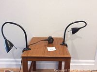 Pair of two black halogen reading lamps mounted on a small wooden table, showing lamp form and flexible necks.