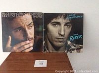 Two Bruce Springsteen vinyl album covers, "The Wild, The Innocent & The E Street Shuffle" and "The River".
