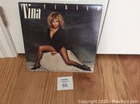 Photo of Tina Turner Private Dancer vinyl album cover showing Tina Turner in black sitting with legs extended on white block.