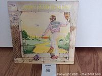 Front cover of Elton John Goodbye Yellow Brick Road double vinyl album showing illustrated artwork of Elton John facing a yellow brick road.