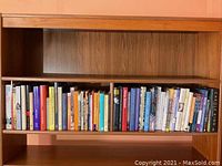 Books arranged on wooden shelves with diverse titles, colors, and sizes visible.