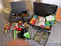 Photo showing black carrying case with K'NEX pieces including rods, connectors, gears, wheels, and an instruction manual titled 'Discovery'.