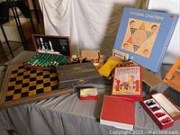 Wide view of all included games and boards on table showing chess board, Twixt, Backgammon, Chinese Checkers, and checkers pieces.