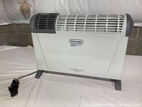 Front view of DeLonghi Safe Heat space heater showing vented front panel and brand label.