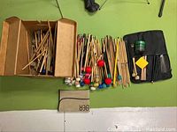 Overview of the complete assortment of mallets and drumsticks laid out on a green floor including a box, a drumstick case, and various sticks.