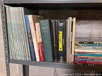 Books on shelving with titles focused on photonics, Persian culture, art deco style, and advertising.