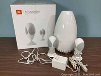 Complete JBL Encounter speaker system with subwoofer, two satellite speakers, power adapter, and original box.