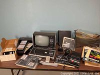 Overall view of table with TRS-80 system, video monitor, tape box, manuals and peripherals