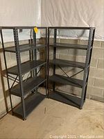 Two metal shelving units placed side by side against a basement wall, showing overall structure and condition.
