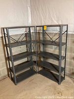 Two black metal shelving units side by side in a basement corner against cinder block walls and plastic sheeting on the upper wall. Both have five shelves and are approximately 30 inches wide, 12 inches deep, and 59 inches tall.