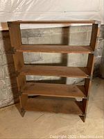 Front view of the wooden bookshelf showing all four shelves and reinforcing metal brackets on corners.