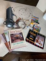 Overview of desk fan, mobiles, jewelry, books and PC game on countertop