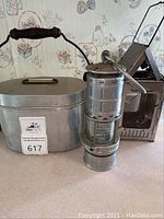 Full view of lunchbox with two different vintage miners style lanterns on the side