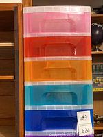 Stack of colorful rainbow plastic storage drawers in vertical container, with pink, red, orange, blue drawers visible