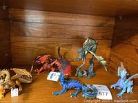 Display shelf with five dragon figurines: gold, red, blue, light blue, and greenish dragons