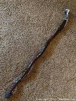 Full-length view of curved wooden walking stick lying on carpet