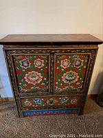 Front view of chest showing two doors, lower drawer and painted floral motifs