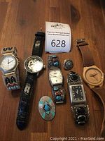 Overview of all five watches and two jewelry pieces on wooden surface
