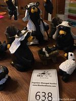 Full view of multiple bear figurines dressed as nativity characters laid on a wooden surface including sheep and baby in manger.