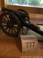 Side view of the entire cannon wagon model showing metal spoked wheels, carriage, barrel, chain, and rope detail