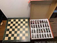Wooden chess board alongside box of King Arthur themed chess pieces, all arranged for view