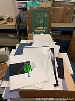 Various matte boards stacked in different colors and sizes with some sketch papers on top