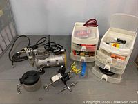Full lot overview on table showing compressor, hoses, storage drawers, holder, airbrush and cleaning pot
