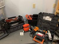 Photo showing full lot: Black & Decker finish sander, Workforce tool tote loaded with small tools, two-compartment plastic tote with orange extension cord, Rigid brad nailer case