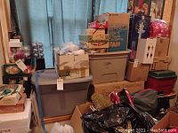 Photo showing five or more stacked plastic and cardboard boxes with Christmas decorations inside packed and labeled.