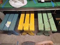 Overview of three picnic benches painted blue, yellow, and green showing their size and condition