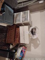 Overall view of craft and sewing supplies in various storage boxes, baskets, and plastic drawers stacked in a corner.