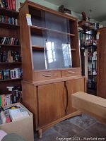 Front view of mid-century modern wooden cabinet with glass sliding doors on top, two drawers in middle, two cabinets below