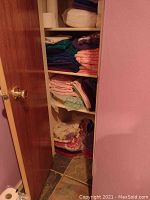 Full view of closet shelves filled with various colors of folded bath linens such as towels and washcloths