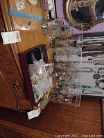 Overview of a wooden dresser with multiple pairs of hanging earrings on clear acrylic display stand and bags of earrings on the surface