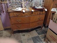 Full front view of dresser showing three drawers, carved legs and top surface with items