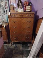 Front view of five-drawer chest showing overall condition, drawer alignment, metal hardware and carved apron.