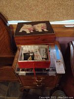 Closed wooden box with white dogs image on lid and open red box with jewelry inside.