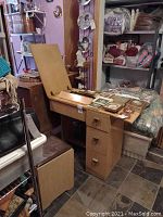 Full view of mid-century modern wooden console sewing machine with matching storage seat. Console top open revealing sewing machine interior closed when not in use.
