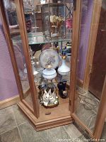 View of lower glass shelf with white ceramic perfume bottles, floral plate, and bunny figurine